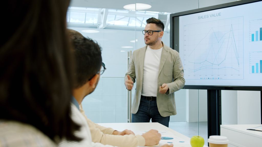 Business presentation with charts discussing sales growth in conference room.